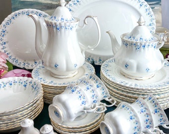 Peut inclure: Service à thé complet en porcelaine blanche avec des motifs floraux bleus. L'ensemble comprend des tasses, des soucoupes, des théières, un plat de service, des bols et des sucriers. Le logo Royal Albert England est visible.