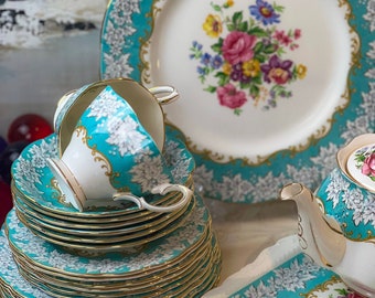 May include: A set of turquoise and gold teacups, saucers, and a teapot with a floral design. The set includes a stack of 12 saucers and a matching tea tray.