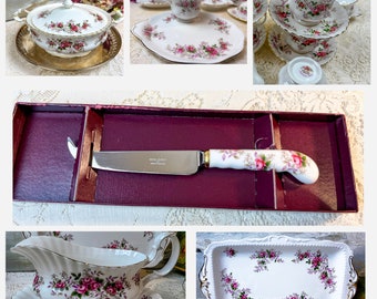 May include: A set of Royal Albert Old Country Roses fine china, including a covered sugar bowl, a creamer, a serving plate, a teacup and saucer, and a cheese knife in a box. The china features a floral pattern with pink roses and green leaves.