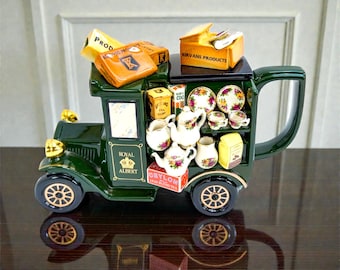May include: A decorative ceramic tea set in the shape of a vintage truck. The dark green truck features gold accents, a large handle, and is filled with miniature teacups, teapots, and boxes of tea. The Royal Albert logo is visible on the side.