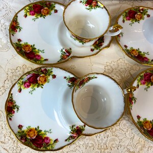 May include: A set of three white teacups and saucers with a gold rim and floral pattern. The saucers have a small side plate for snacks.