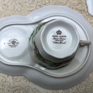May include: A white Royal Albert Silver Birch bone china teacup and saucer set. The teacup is placed on a matching tray with a floral design. The set includes the text "Royal Albert Bone China England Silver Birch".