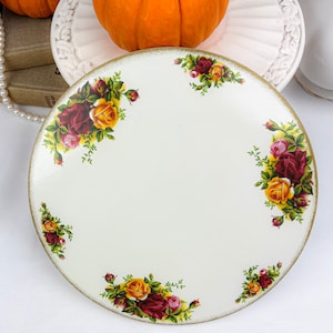 Könnte beinhalten: Weiße Keramikplatte mit goldfarbenem Rand und floralem Design mit roten, gelben und rosa Rosen. Die Platte ist mit einem zarten goldenen Rand verziert.