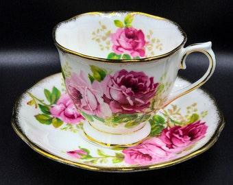 May include: A white teacup and saucer with a pink rose floral pattern and gold trim.