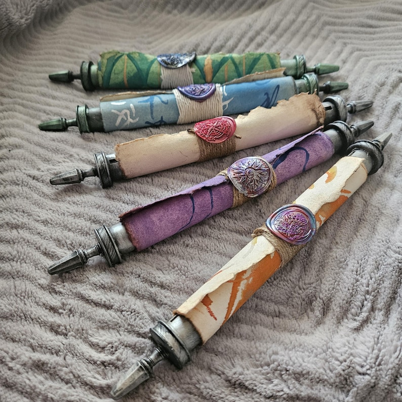 May include: Five decorative scrolls with different colored papers and wax seals. The scrolls are tied with twine and have metal tips.
