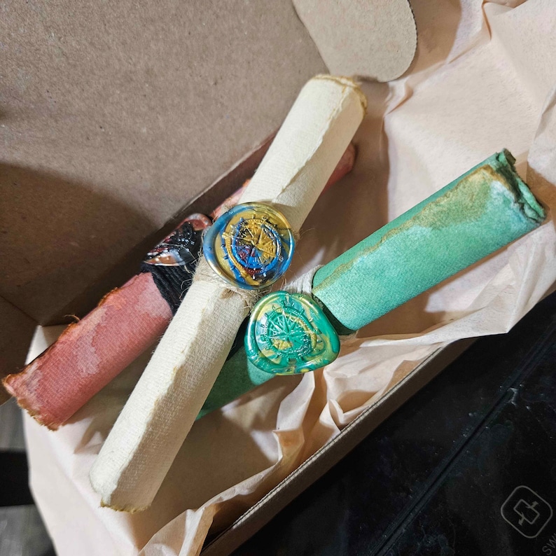 May include: Three rolled up scrolls with wax seals. The seals are decorated with a compass design and are in shades of blue, green, and yellow.