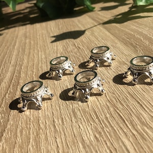 Könnte beinhalten: Fünf silberne Metallständer in Kronenform zum Ausstellen von Kristallen oder anderen kleinen Gegenständen. Die Ständer sind auf einer Holzoberfläche angeordnet.