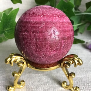 Könnte beinhalten: Eine weiße Keramik-Tasse mit schwarzem Henkel und dem Text "But First, Coffee" in schwarzer, handschriftlicher Schrift. Die Tasse steht auf einer weißen Oberfläche.