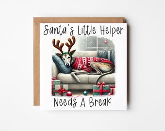 Peut inclure: Une carte de Noël illustrant un chien en dessin animé portant un pull rouge et blanc et des bois de renne, dormant sur un canapé avec des cadeaux et des décorations de Noël autour de lui. Le texte sur la carte dit "Santa's Little Helper Needs A Break".
