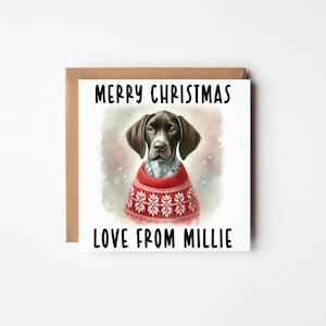 May include: A Christmas card with a German Shorthaired Pointer wearing a red sweater with white snowflake patterns. The card has the text "MERRY CHRISTMAS" at the top and "LOVE FROM MILLIE" at the bottom, set against a soft, watercolour background.