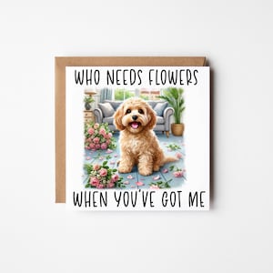 May include: Greeting card featuring a light brown dog illustration. The card has the text "WHO NEEDS FLOWERS WHEN YOU'VE GOT ME". The dog is on a blue floor with pink flower petals scattered around.