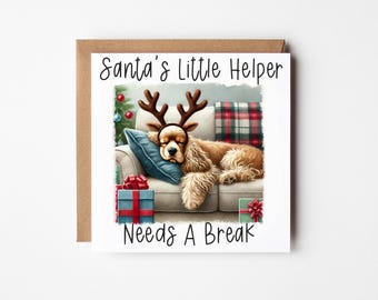 Könnte beinhalten: Eine Weihnachtskarte mit einem Hund, der ein Rentiergeweih trägt und auf einem Sofa mit Geschenken schläft. Die Karte lautet "Santa's Little Helper Needs A Break".