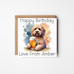May include: A square birthday card with a brown border. It features a cartoon dog holding a pint of beer. The text "Happy Birthday" is at the top, and "Love From Amber" is at the bottom. The background has watercolour splashes of blue, orange, and yellow.