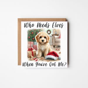 May include: A Christmas card with a golden puppy illustration, a Christmas tree, and presents. The text on the card reads "Who Needs Elves When You've Got Me?" A Santa hat is on the floor.