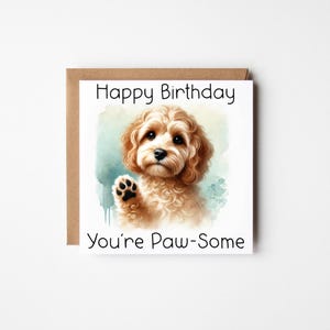 May include: A square birthday card featuring a watercolour illustration of a light brown, curly-haired dog. The card has the text "Happy Birthday" and "You're Paw-some" printed in black. The card is set against a brown envelope.