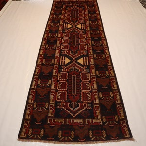 May include: A long, narrow rug with a traditional geometric pattern in shades of red, brown, and cream. The rug has a fringe border.