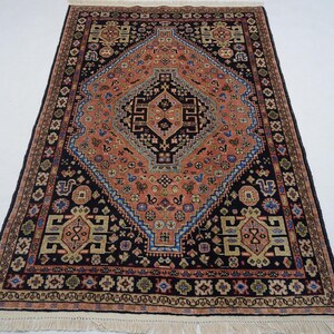 May include: A traditional Persian rug with a central diamond-shaped medallion in shades of red, orange, and blue. The rug has a black background and intricate floral and geometric patterns.