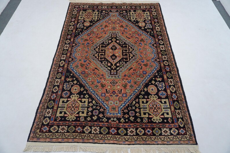 May include: A traditional Persian rug with a central diamond-shaped medallion in shades of red, orange, and blue. The rug has a black background and intricate floral and geometric patterns.