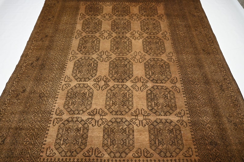 K&ouml;nnte beinhalten: Ein brauner und schwarzer Teppich mit geometrischem Muster. Der Teppich hat ein zentrales Feld mit einem sich wiederholenden Muster aus Achtecken und Quadraten. Der Rand ist ein schmales Band mit geometrischen Mustern.
