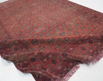 Puede incluir: Una alfombra rectangular con un color base rojo intenso que presenta patrones geométricos oscuros repetitivos y motivos octogonales. La alfombra tiene un diseño denso e intrincado en toda la superficie y un borde con flecos en el lado corto.