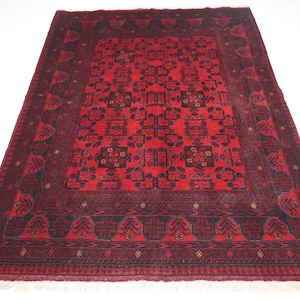 May include: A red and black patterned rug with a detailed geometric design. The rug has a fringe border.
