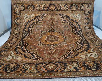 May include: A rectangular area rug featuring a central medallion design in shades of black, brown, tan, and cream. The rug displays intricate floral and paisley patterns throughout the field and a wide, detailed border with repeating motifs.