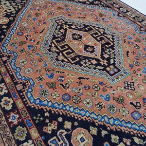 May include: A vintage rug with a central medallion design in shades of pink, blue, and black. The rug features intricate floral patterns and geometric motifs.