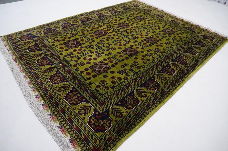 May include: A green rug with a traditional Persian design. The rug has a dark blue border with red and white accents. The center of the rug is a light green color with a repeating pattern of flowers and leaves.