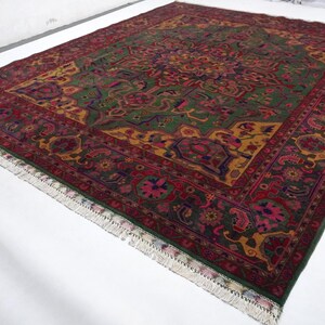 May include: A traditional Persian rug with a green, red and gold colour scheme. The rug features intricate floral and geometric patterns.