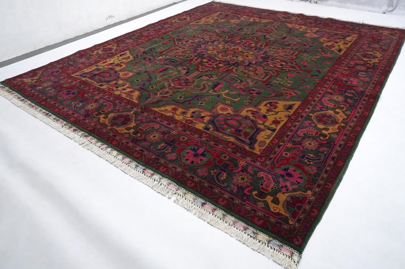 May include: A traditional Persian rug with a green, red and gold colour scheme. The rug features intricate floral and geometric patterns.