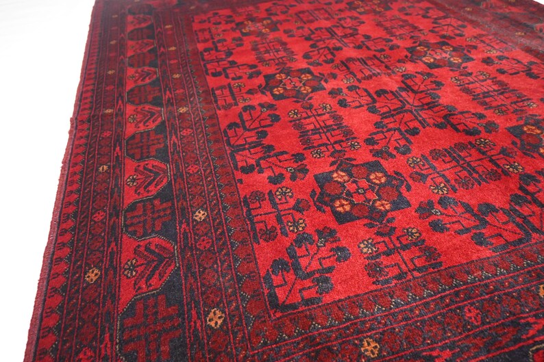 May include: A red and black patterned rug with a traditional design. The rug has a dark border with intricate details and a central field with repeating motifs.