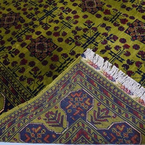 May include: A green and burgundy rug with a geometric pattern. The rug has a fringe border.