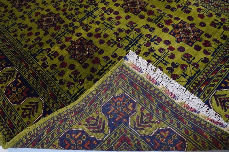 May include: A green and burgundy rug with a geometric pattern. The rug has a fringe border.