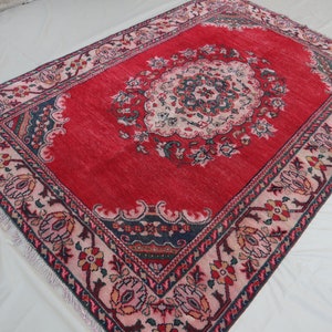 May include: A red rug with a floral pattern and a central medallion. The rug has a pink and black border with intricate details.