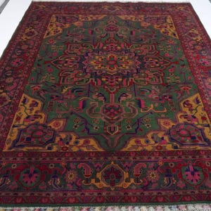 May include: A traditional Persian rug with a green, red and gold colour scheme. The rug features a central medallion with intricate floral and geometric patterns. The rug has a fringed border.