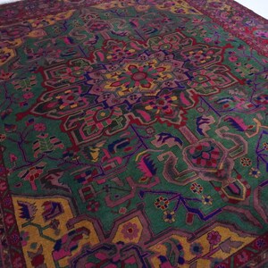 May include: A vintage Persian rug with a colourful geometric design. The rug features a central medallion with intricate details and a border with repeating patterns. The colours include shades of red, green, blue, yellow, and pink.