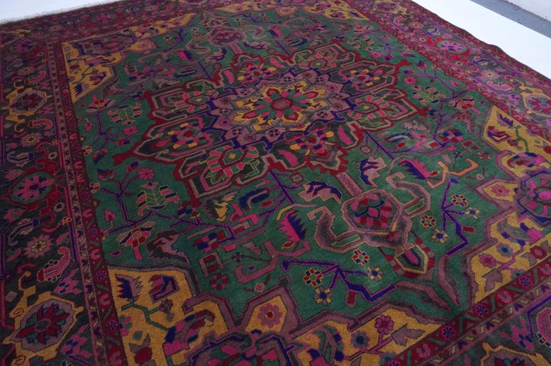 May include: A vintage Persian rug with a colourful geometric design. The rug features a central medallion with intricate details and a border with repeating patterns. The colours include shades of red, green, blue, yellow, and pink.
