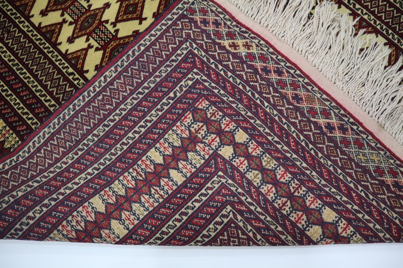 May include: Close-up of a red, white, and blue patterned rug with fringe. The rug has a geometric design with intricate details.