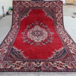 May include: A red rug with a floral pattern and a central medallion. The rug has a fringe border and is made of wool.