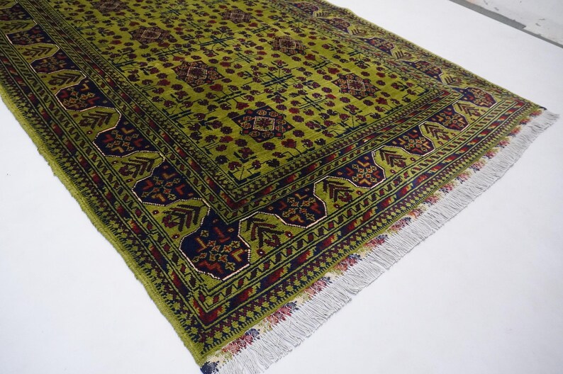 May include: A green rug with a traditional Persian design. The rug has a dark blue border with red and yellow accents. The rug has a fringe on all sides.
