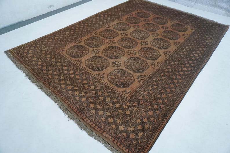 May include: A rectangular, brown rug with a central pattern of repeating octagons. The rug has a dark brown border with a geometric design and fringed edges. The color palette is primarily brown and tan, creating a warm, inviting aesthetic.