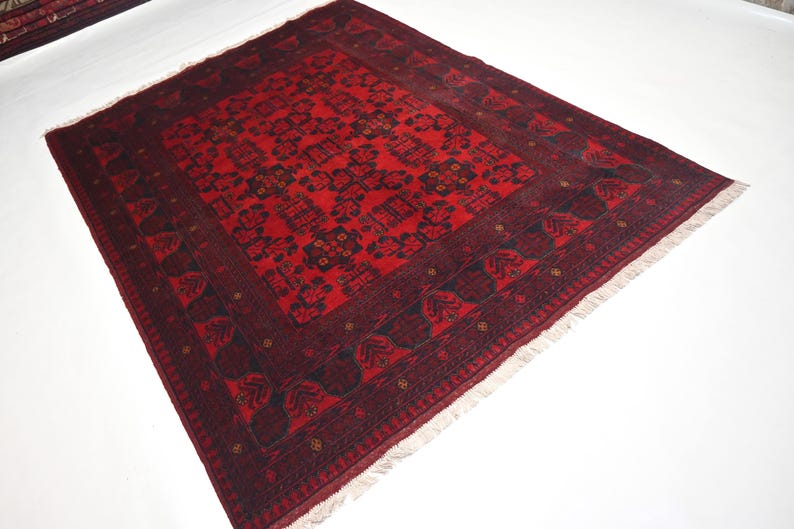 May include: A red and black patterned rug with a fringe border. The rug has a traditional design with intricate details.