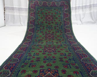 May include: A green runner rug with a traditional Persian design. The rug has a dark blue border with red and white accents. The center of the rug features a repeating pattern of green leaves and flowers.