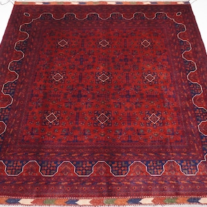 May include: A red, blue, and white patterned rug with a geometric design. The rug has a fringe border.