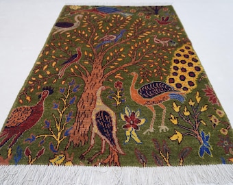 May include: A rectangular green rug with a tree and bird design. The tree trunk is brown, with orange and yellow leaves. Birds in various colors are scattered throughout the design. The rug has a white fringe.