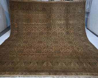 Puede incluir: Una alfombra rectangular grande con una base de color marrón intenso y complejos patrones geométricos repetitivos en un tono más oscuro. El diseño incluye un borde decorativo ancho con motivos estilizados y flecos en el borde inferior.