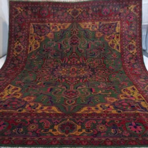 May include: A large, intricately patterned rug with a central medallion in shades of green, red, and gold. The rug has a border with floral and geometric designs.