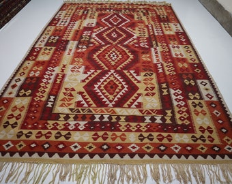 May include: A traditional red, orange, and cream colored rug with a geometric pattern. The rug has a fringe border.