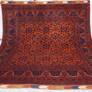 May include: A traditional Persian rug with a red background and intricate blue and white geometric patterns. The rug has a thick fringe border.