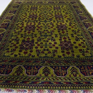 May include: A green rug with a geometric pattern in shades of red, blue, and green. The rug has a fringe border.